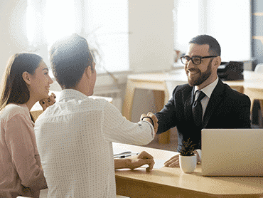 three people at a table with a laptop shaking hands after bad credit loan agreement